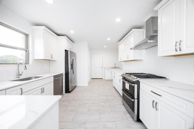 kitchen featuring a sink, stainless steel appliances, white cabinets, and wall chimney range hood