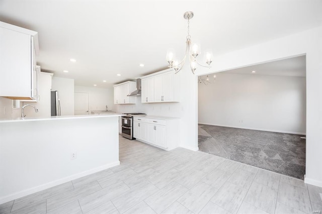 kitchen featuring open floor plan, light countertops, white cabinets, stainless steel appliances, and wall chimney exhaust hood