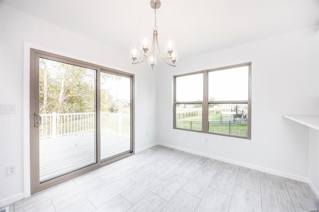 empty room with baseboards, a notable chandelier, and a healthy amount of sunlight