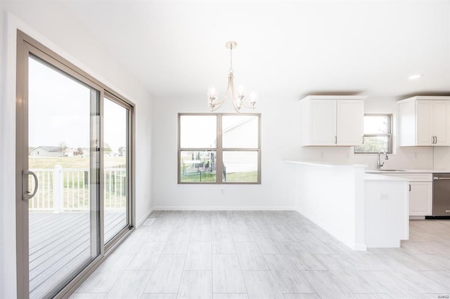 kitchen with a sink, white cabinetry, a peninsula, light countertops, and dishwasher