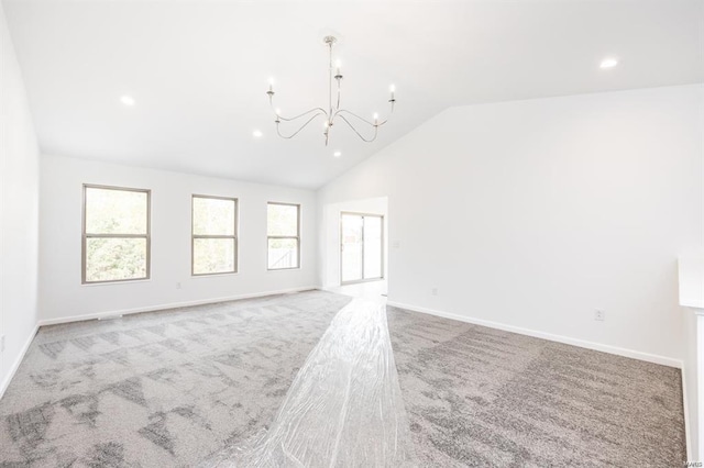 unfurnished living room featuring lofted ceiling, a notable chandelier, a wealth of natural light, and carpet floors