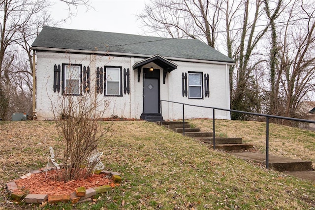 bungalow-style house with a shingled roof, entry steps, fence, and a front lawn