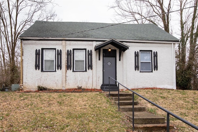 bungalow-style house with entry steps, a front lawn, and roof with shingles