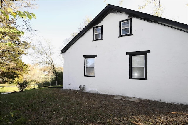 view of side of property with a lawn and stucco siding