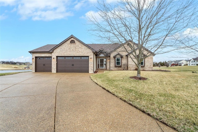 french country inspired facade with brick siding, roof with shingles, an attached garage, a front yard, and driveway