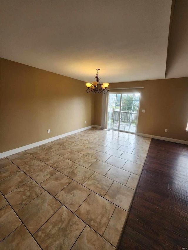 spare room featuring an inviting chandelier and baseboards