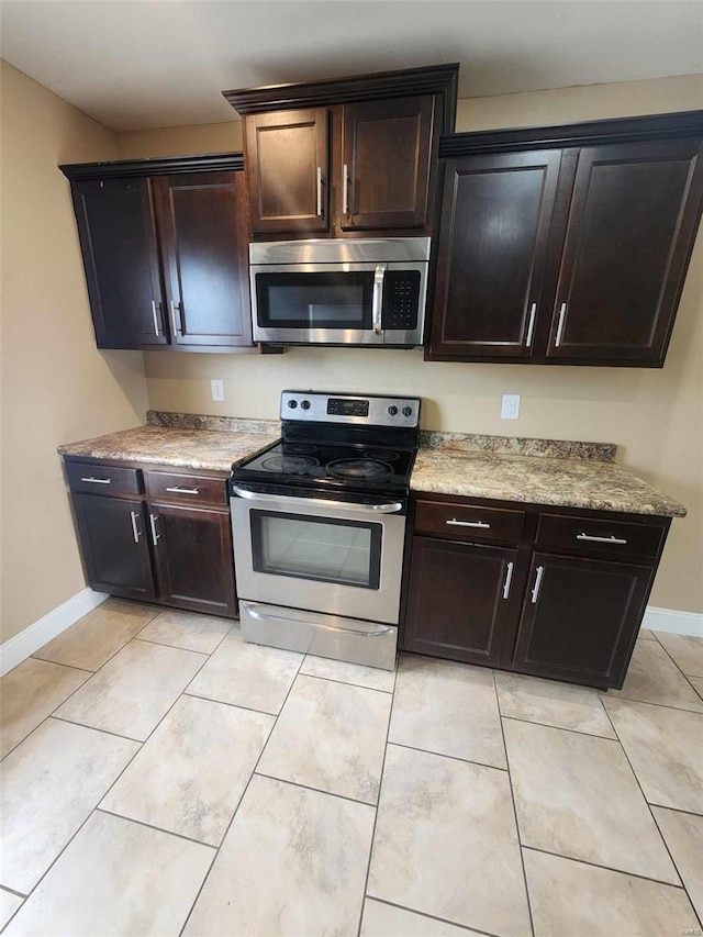 kitchen with dark brown cabinets, appliances with stainless steel finishes, light countertops, and baseboards