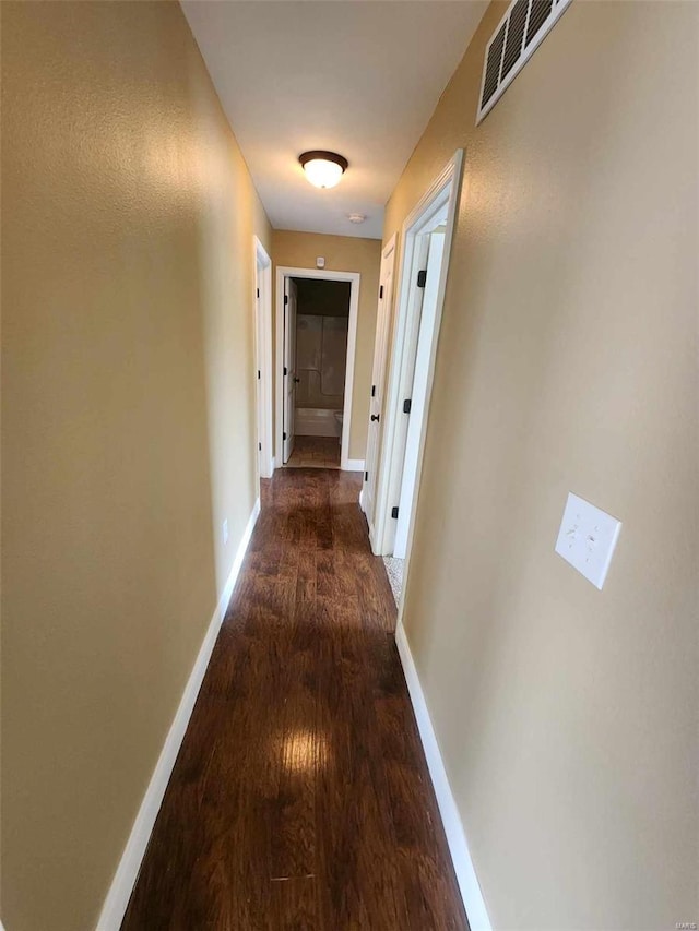 corridor with visible vents, baseboards, and wood finished floors