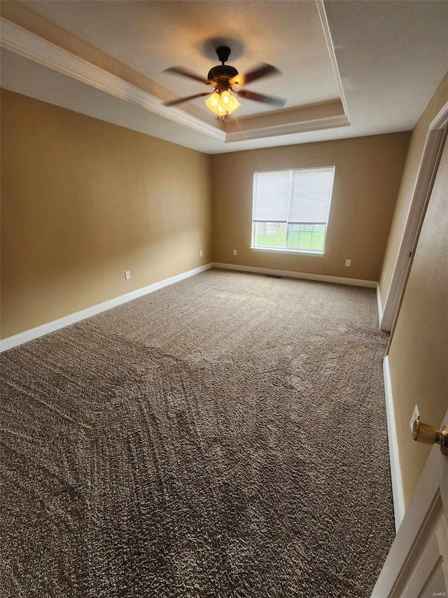 unfurnished room with a ceiling fan, a tray ceiling, carpet, and baseboards