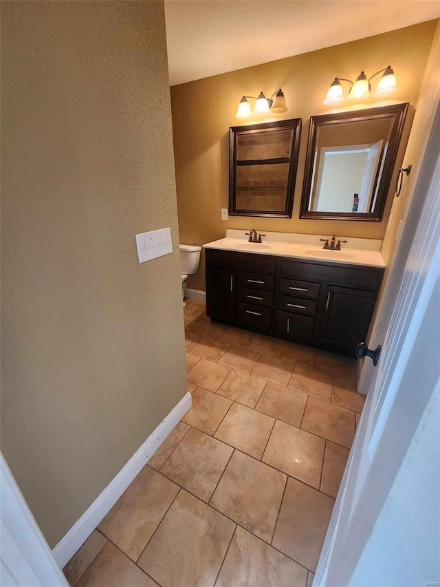 full bath with toilet, baseboards, a sink, and tile patterned floors