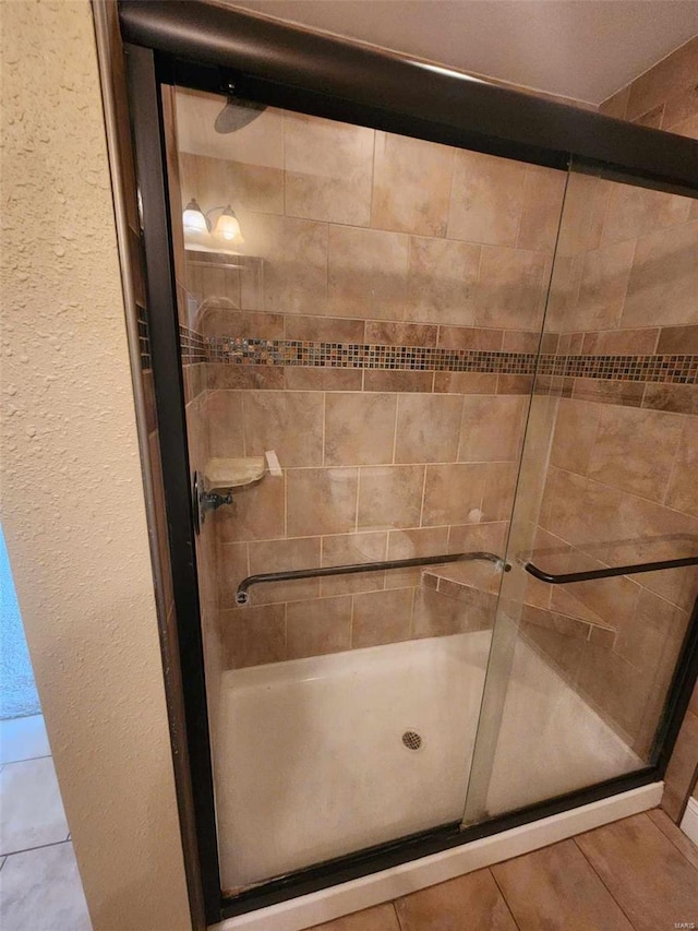 full bath with a shower stall and a textured wall