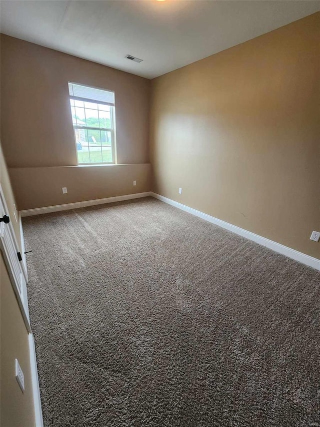 empty room featuring carpet flooring, visible vents, and baseboards