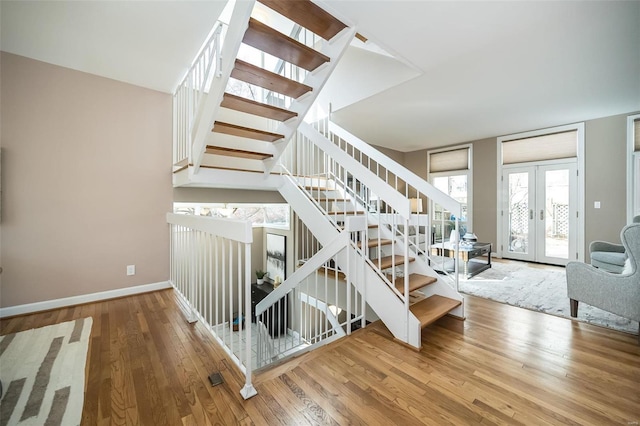 stairs with french doors, baseboards, and hardwood / wood-style flooring