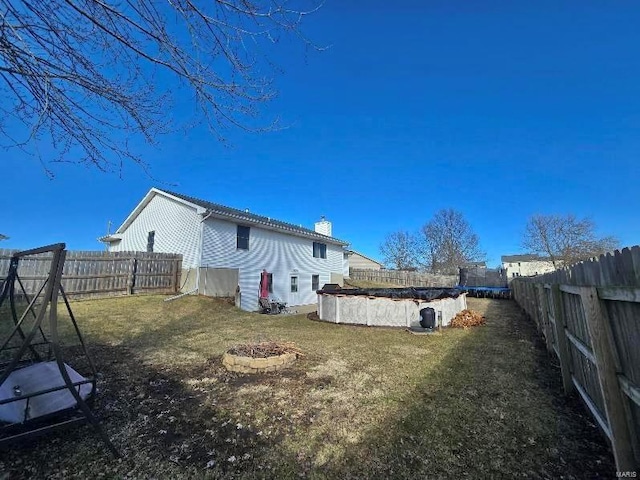 exterior space featuring an outdoor fire pit, a chimney, a fenced backyard, and a yard