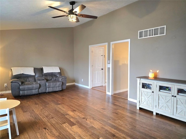 living room featuring ceiling fan, wood finished floors, visible vents, baseboards, and vaulted ceiling