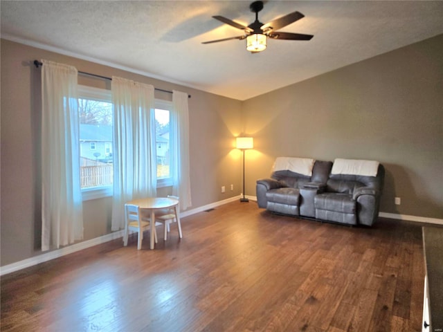 living room with baseboards, dark wood finished floors, and a ceiling fan