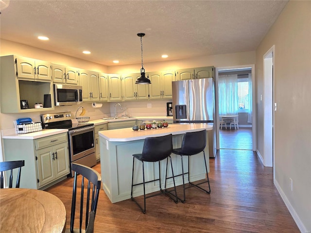 kitchen with dark wood-style floors, a center island, stainless steel appliances, light countertops, and a sink