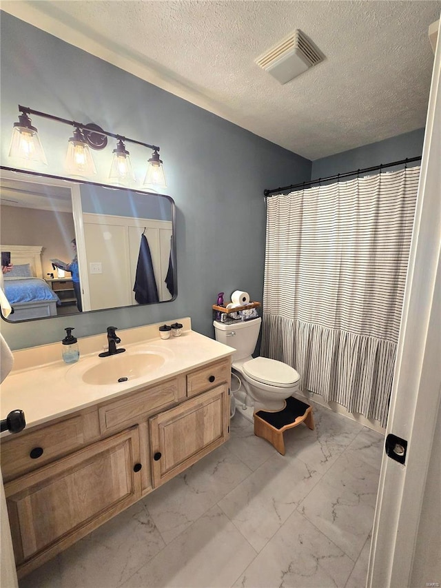 full bathroom featuring toilet, marble finish floor, vanity, and visible vents