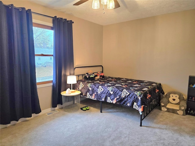 carpeted bedroom featuring a textured ceiling, ceiling fan, and visible vents