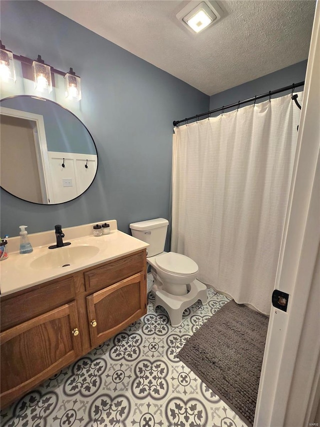 full bathroom with toilet, tile patterned flooring, a textured ceiling, and vanity