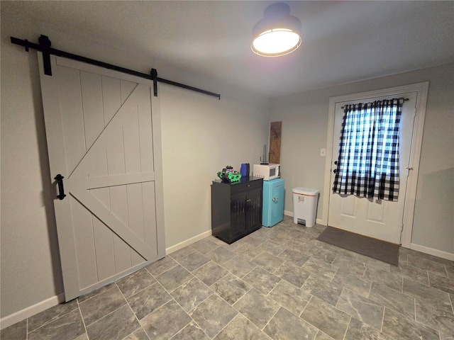 entrance foyer with a barn door, stone finish floor, and baseboards