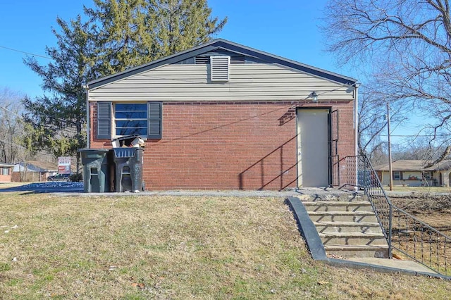 view of side of home featuring brick siding and a yard