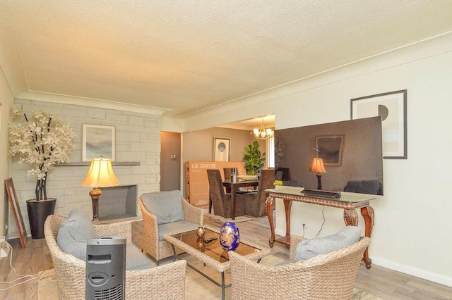 living room with a fireplace, a textured ceiling, wood finished floors, a chandelier, and baseboards