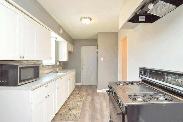 kitchen featuring light countertops, stainless steel microwave, backsplash, gas stove, and white cabinets