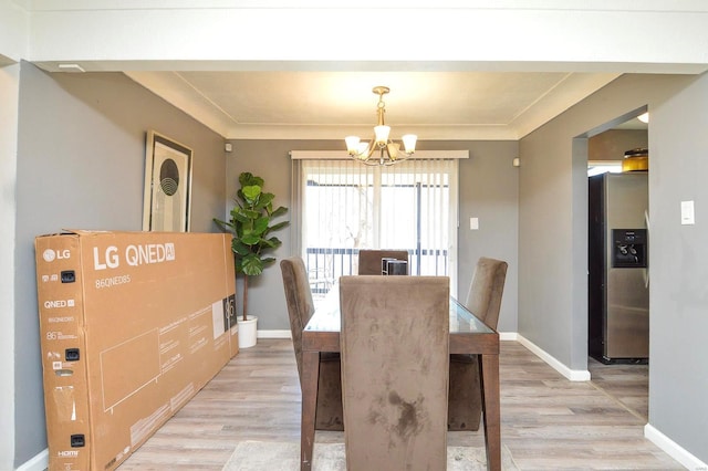 dining room with light wood-style floors, baseboards, and an inviting chandelier