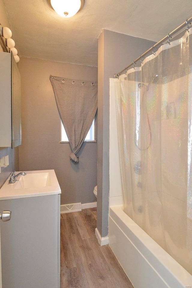 full bath featuring shower / tub combo, baseboards, toilet, wood finished floors, and vanity