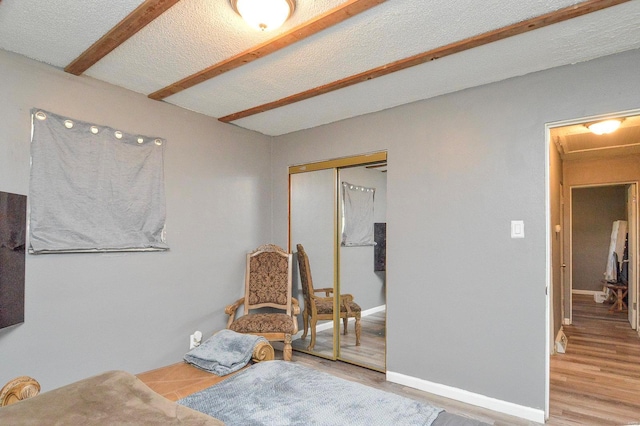 living area featuring a textured ceiling, baseboards, and wood finished floors