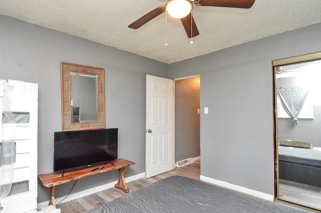 bedroom with a textured ceiling, wood finished floors, a ceiling fan, and baseboards