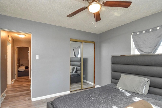 bedroom with baseboards, ceiling fan, wood finished floors, a textured ceiling, and a closet