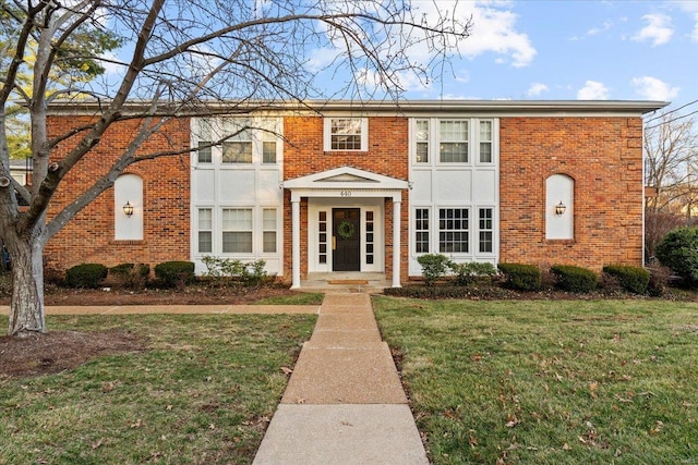 townhome / multi-family property featuring a front lawn and brick siding