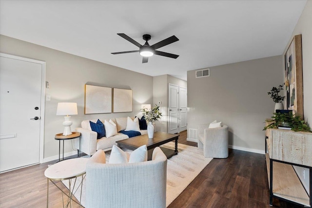 living area featuring baseboards, wood finished floors, visible vents, and a ceiling fan