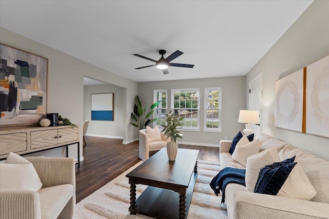 living area with dark wood-style floors, ceiling fan, and baseboards