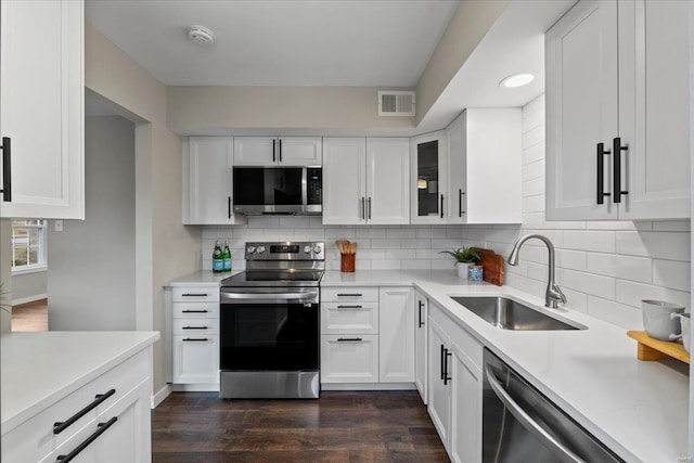 kitchen with dark wood-style floors, stainless steel appliances, visible vents, white cabinetry, and a sink