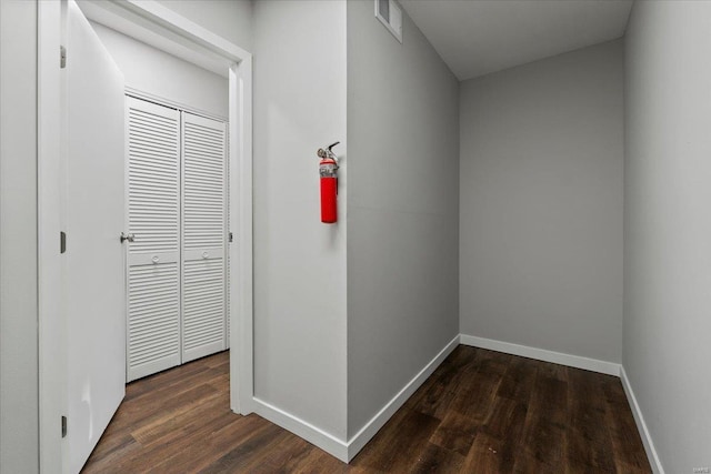 hallway with visible vents, baseboards, and wood finished floors