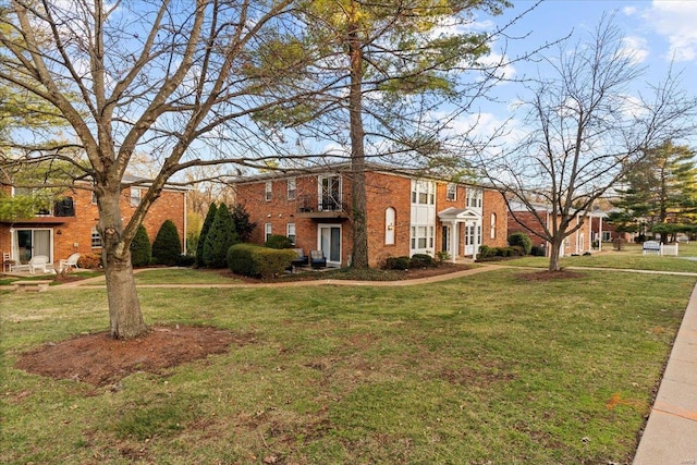 colonial-style house featuring brick siding and a front yard