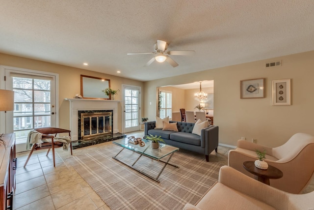 living area with a healthy amount of sunlight, tile patterned floors, visible vents, and a high end fireplace