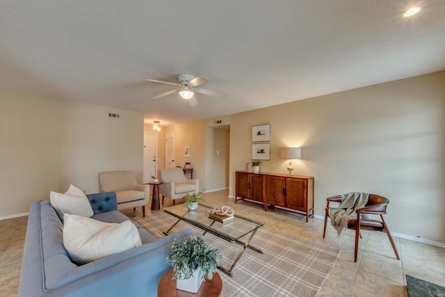 living area featuring baseboards, visible vents, ceiling fan, and a textured ceiling