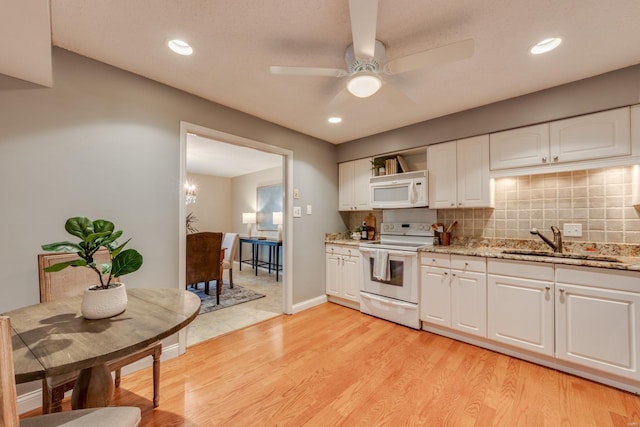 kitchen with white appliances, tasteful backsplash, light wood-style floors, and a sink