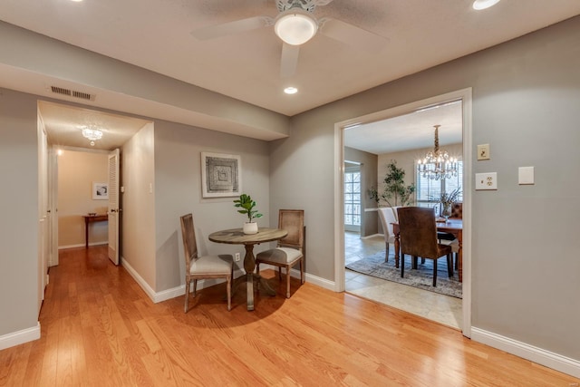 dining space featuring visible vents, ceiling fan with notable chandelier, light wood-style flooring, and baseboards