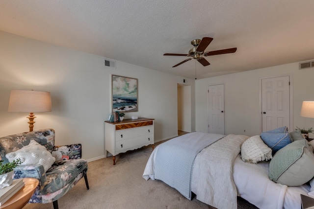 bedroom featuring ceiling fan, visible vents, a textured ceiling, and light colored carpet