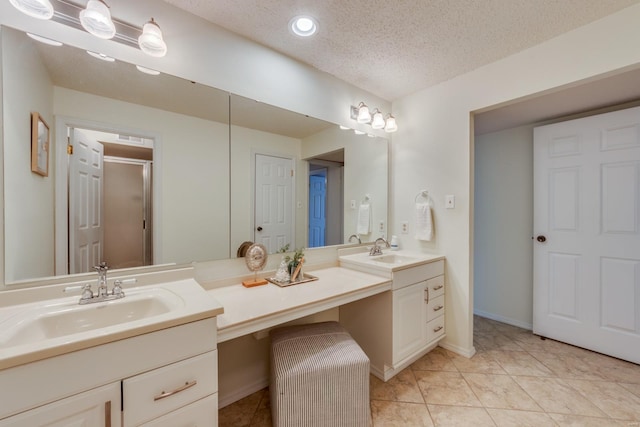 bathroom featuring tile patterned floors, a sink, a textured ceiling, and double vanity