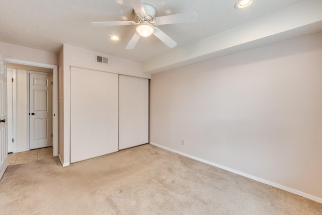 unfurnished bedroom featuring a closet, light colored carpet, visible vents, ceiling fan, and baseboards