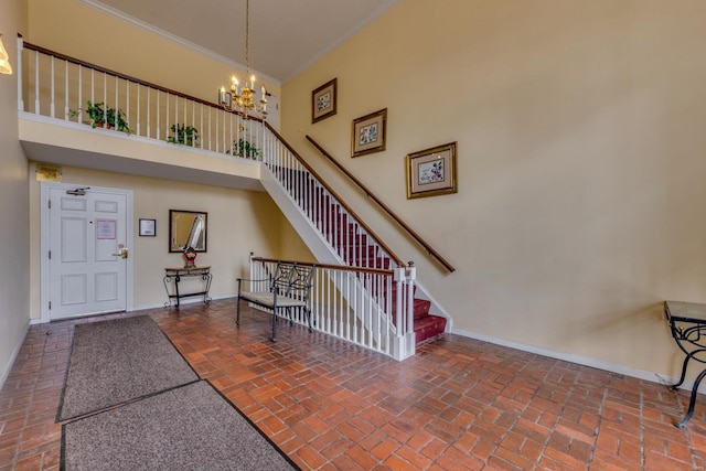 stairway with baseboards, brick floor, a towering ceiling, and an inviting chandelier