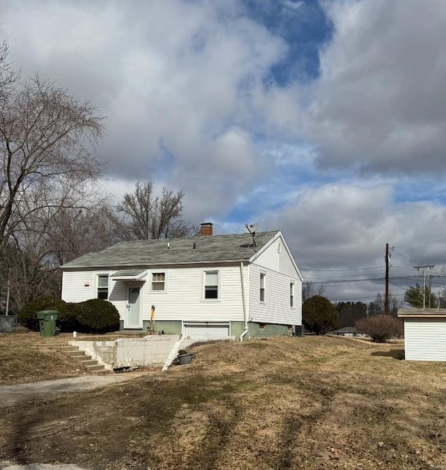 rear view of house with a chimney and an attached garage