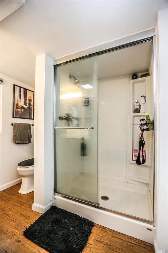 full bathroom with toilet, wood finished floors, and a stall shower