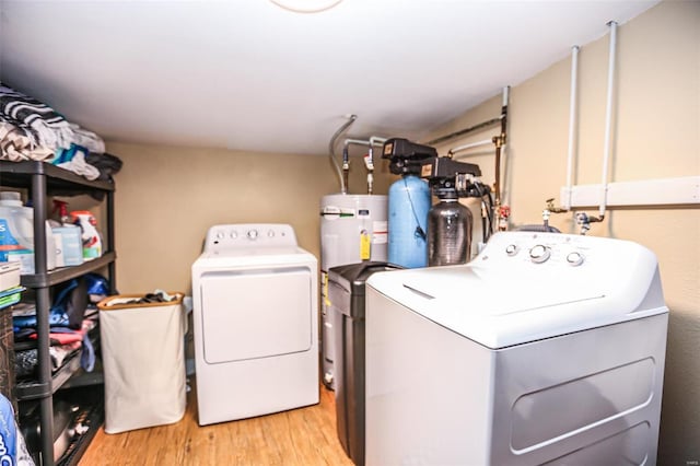 laundry room with washer and dryer, light wood-type flooring, and electric water heater